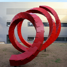 Kunstförmige rote Spirale vor dem lichtreflektierenden PET-Zentrum