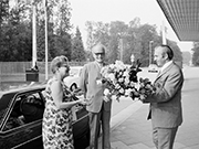 Eine Besucherin bekommt einen Blumenstrauß am Haupteingang überreicht.