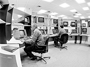 2 Mitarbeiter vor Monitoren im Bedienungsraum des Supercomputers Cray