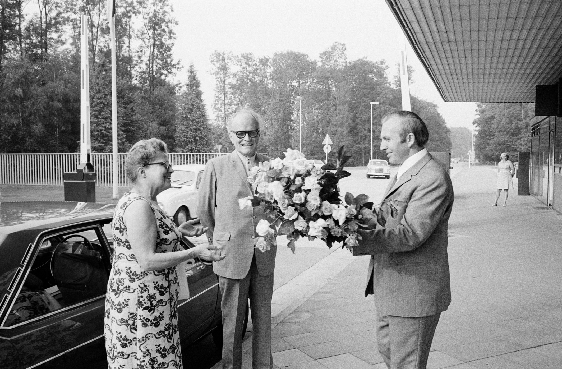 Eine Besucherin bekommt einen Blumenstrauß am Haupteingang überreicht.